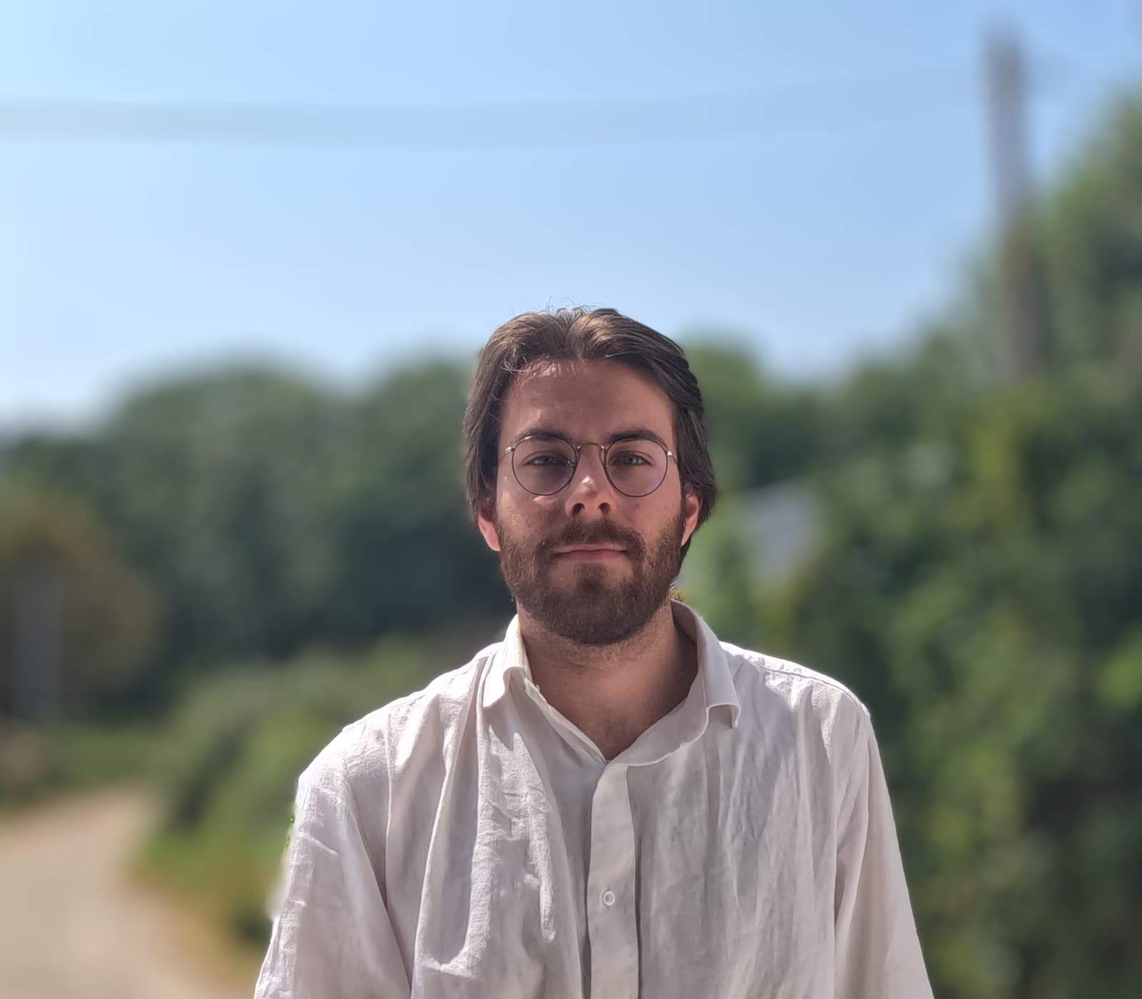Portrait de Joris Flohic en extérieur, chemise blanche en lin, regard vers l'objectif.